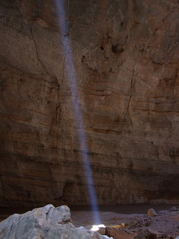 Person am Seil auf ihrem Weg zu der Höhle am Boden von Majlis al Jinn